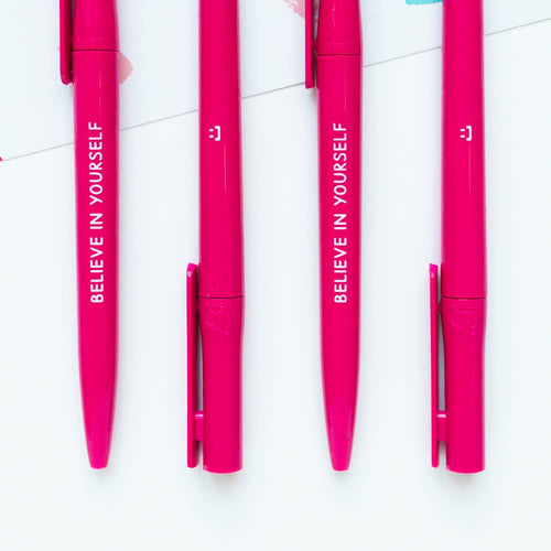 Four pink pens with 'BELIEVE IN YOURSELF' text on a white background