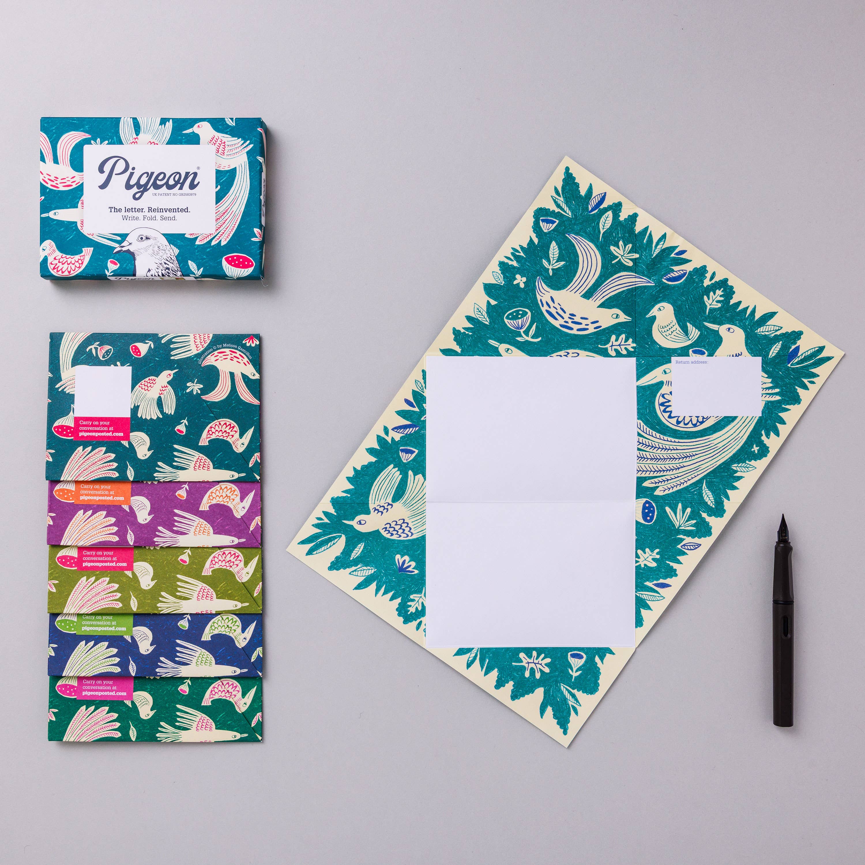 Notebook with bird pattern, colorful packaging, and pen on gray background