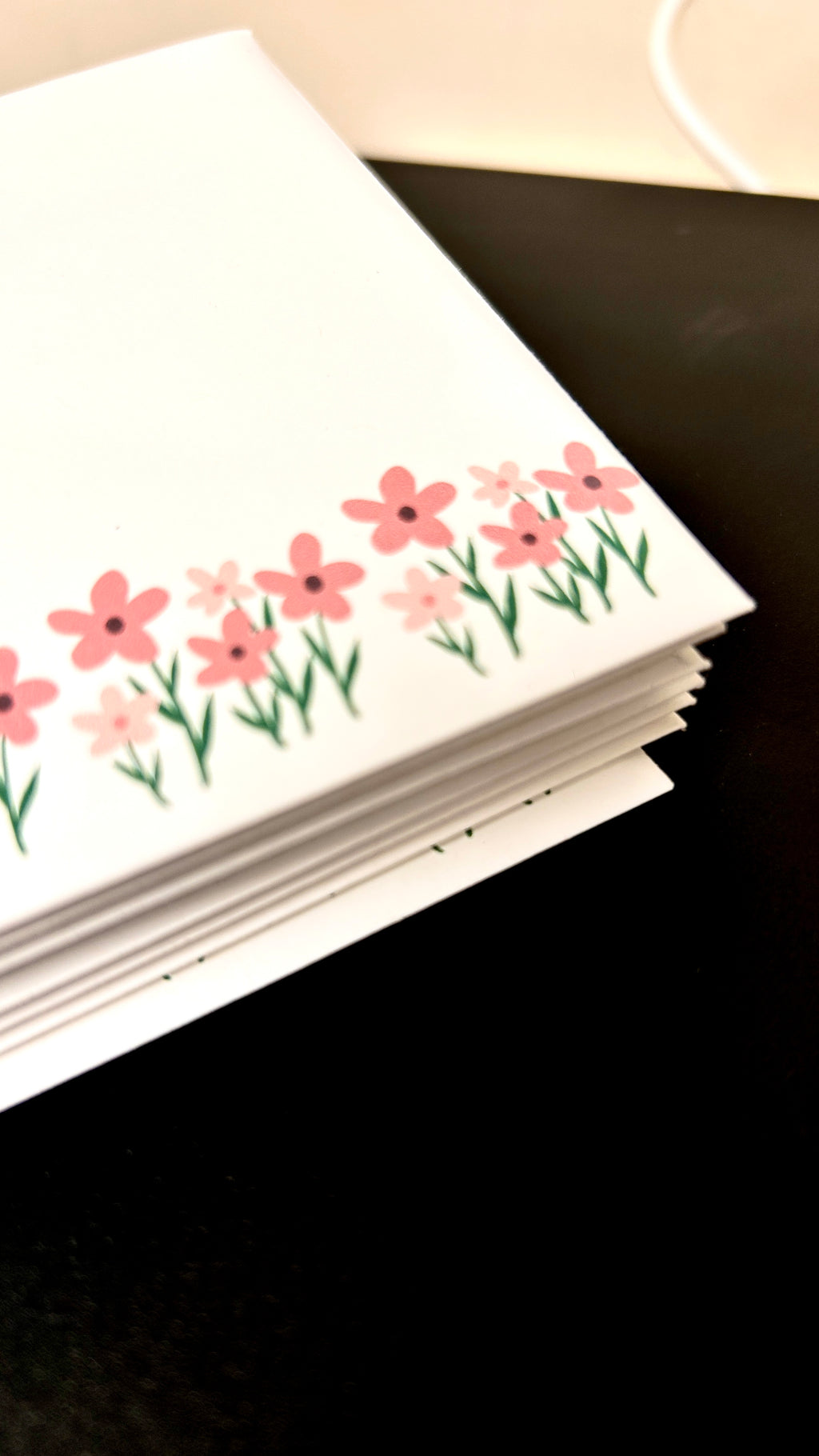 Stack of cards with floral design on a dark surface
