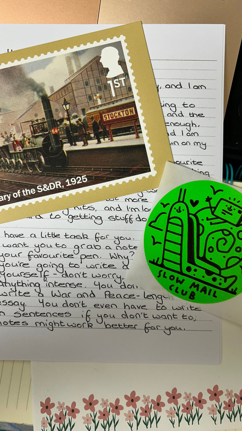 Letter with a vintage stamp and a 'slow mail' sticker on a surface with flowers.