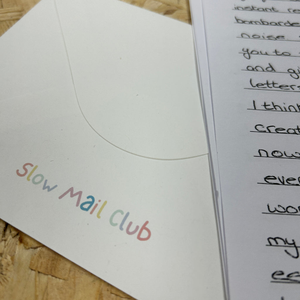 Letter with 'Slow Mail Club' on an envelope against a wooden background