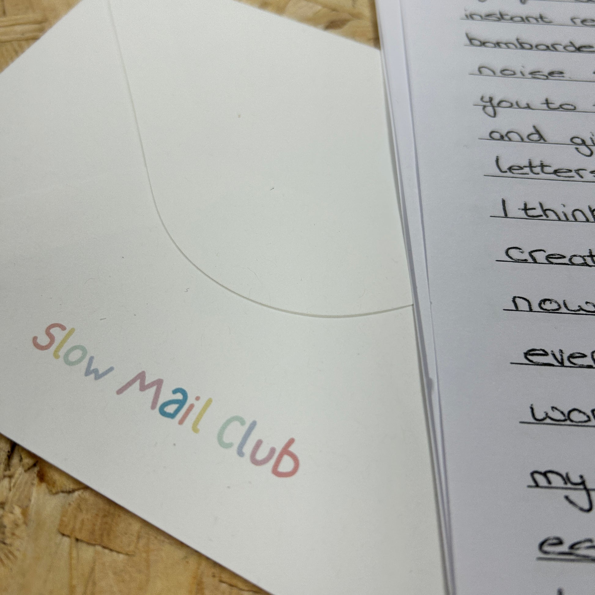 Letter with 'Slow Mail Club' on an envelope against a wooden background