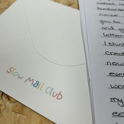 Letter with 'Slow Mail Club' on an envelope against a wooden background